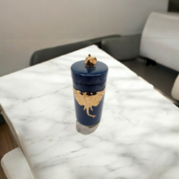 A Blue color candy jar with gold elephant engraved placed on a table