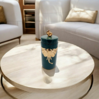 A green color candy jar with gold elephant engraved placed on a table