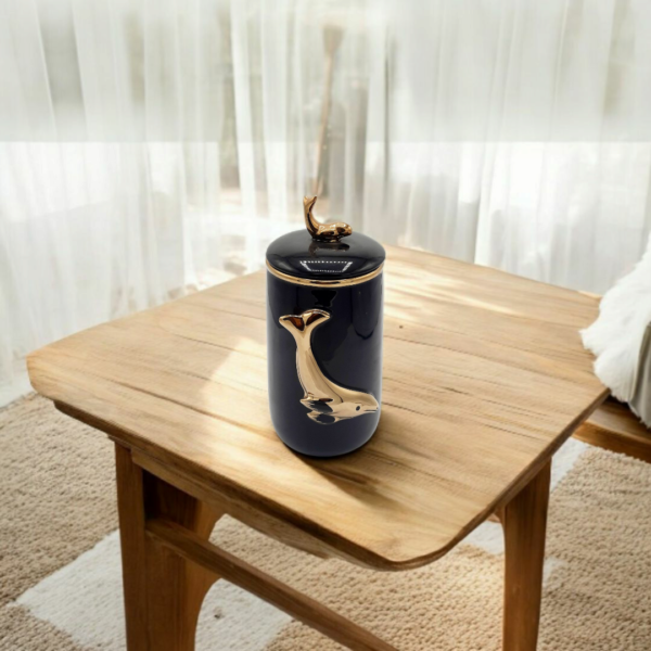 A Black color candy jar with gold fish engraved placed on a table
