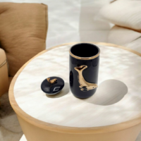 A Black color candy jar with gold fish engraved placed on a table