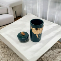 A green color candy jar with gold elephant engraved placed on a table
